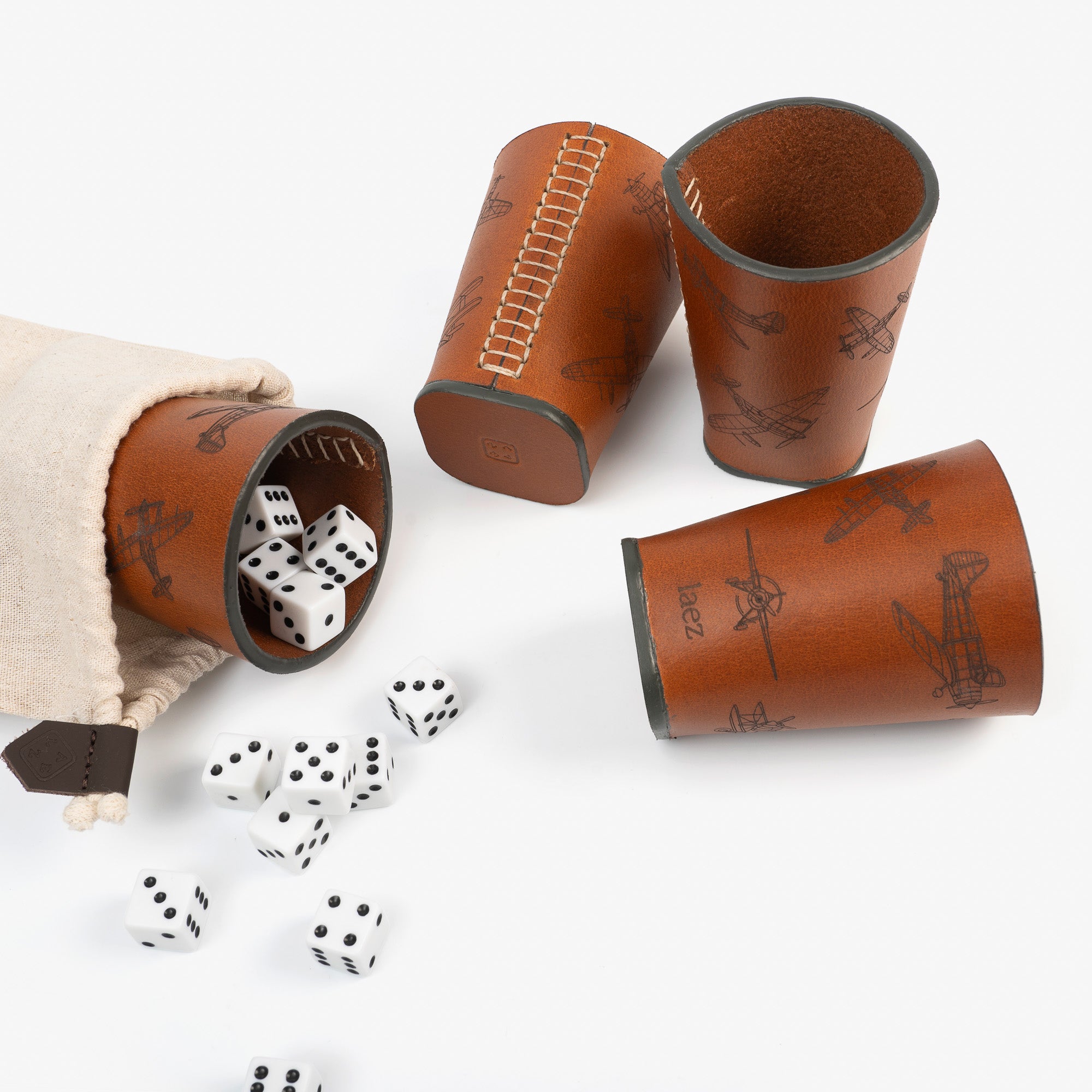 Three dice cups arranged neatly beside a bag filled with colorful dice, ready for a game night.