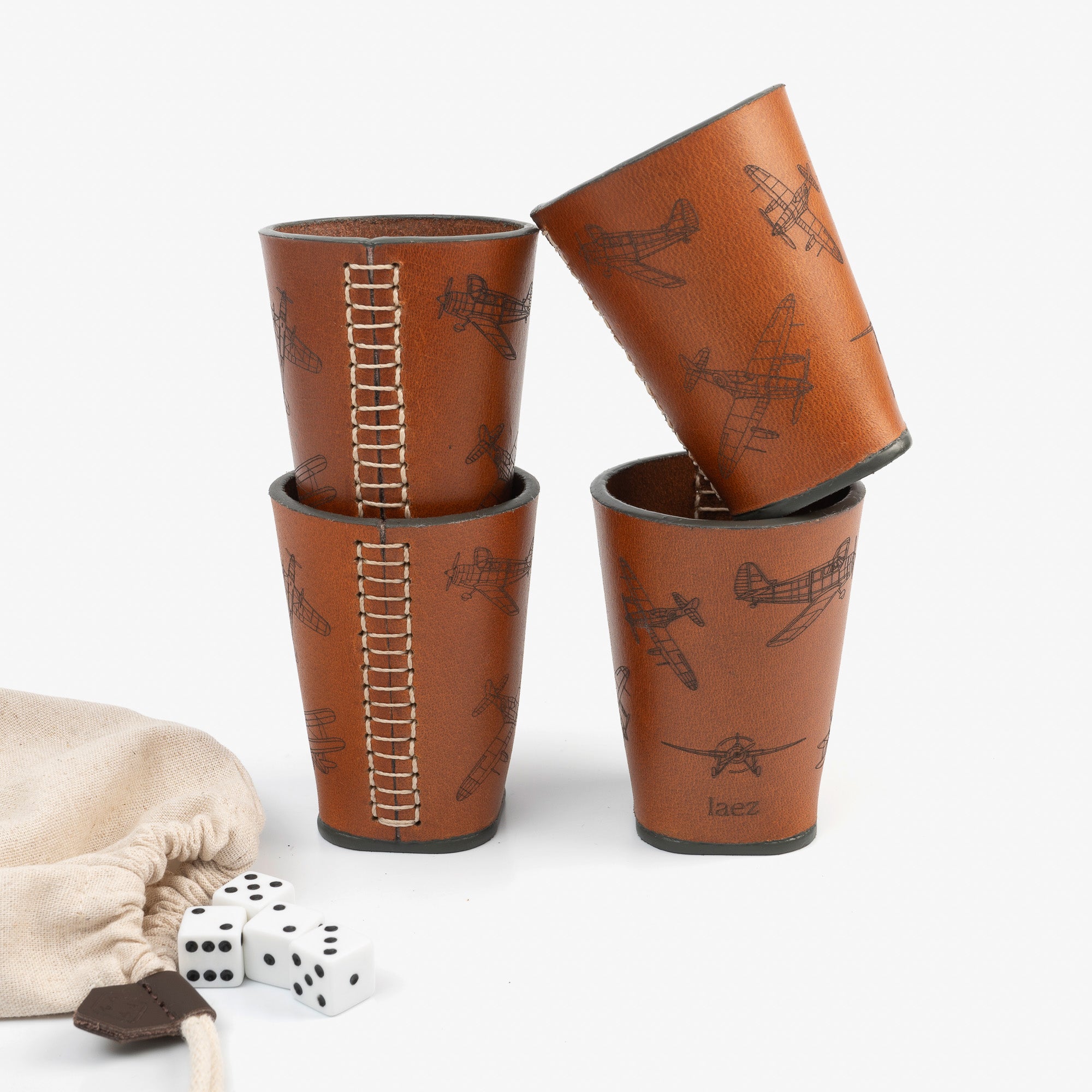 Four dice cups arranged neatly beside a bag filled with dice, ready for a game night.
