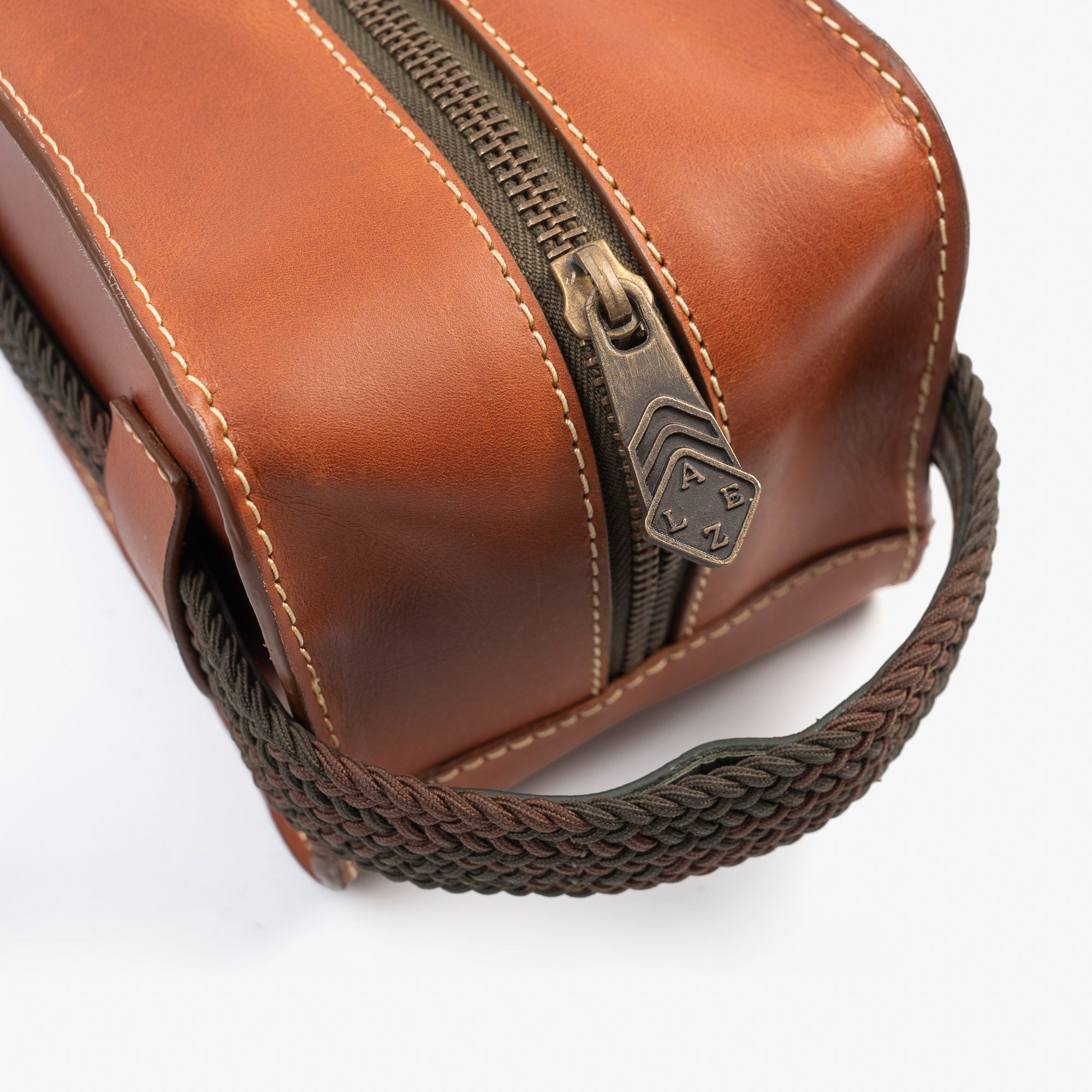 A brown leather travel pouch containing a toothbrush, toothpaste, and various toiletry items for personal care.