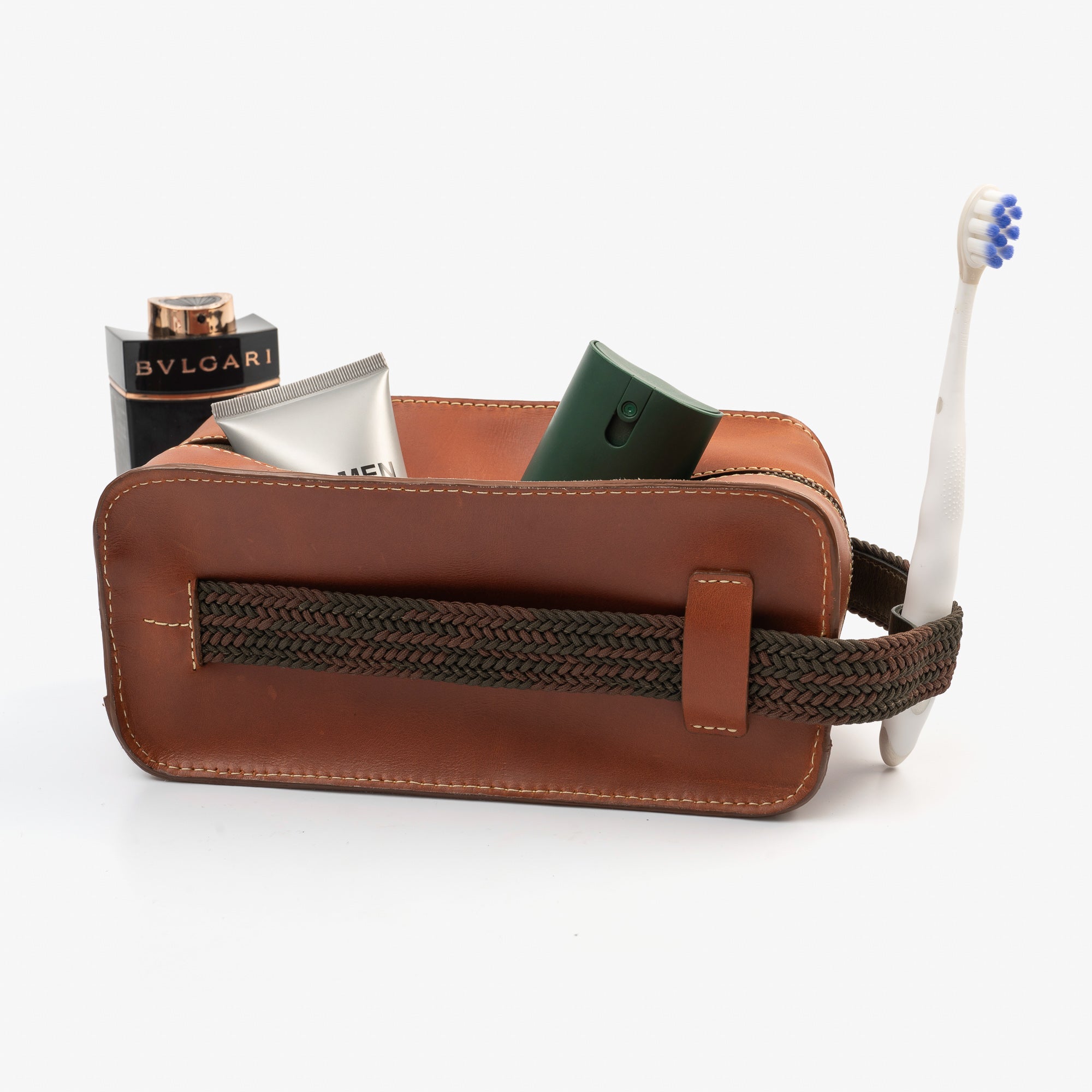 A brown leather travel pouch containing a toothbrush, toothpaste, and various toiletry items for personal care.