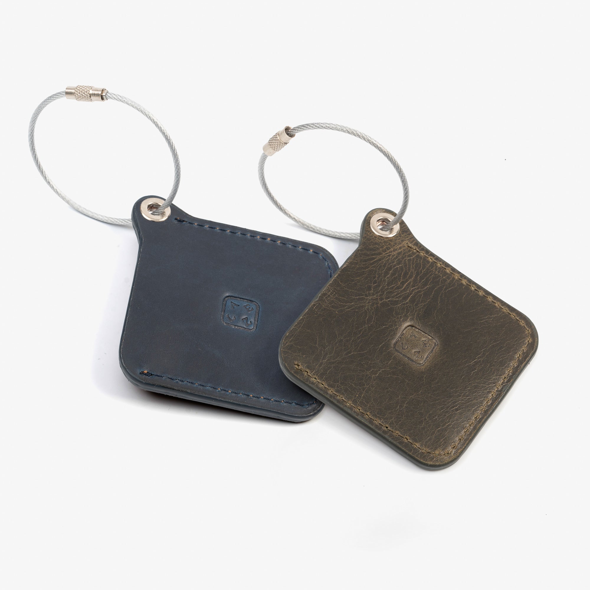 Two leather luggage tags with metal rings, elegantly designed for travel organization and personalization.