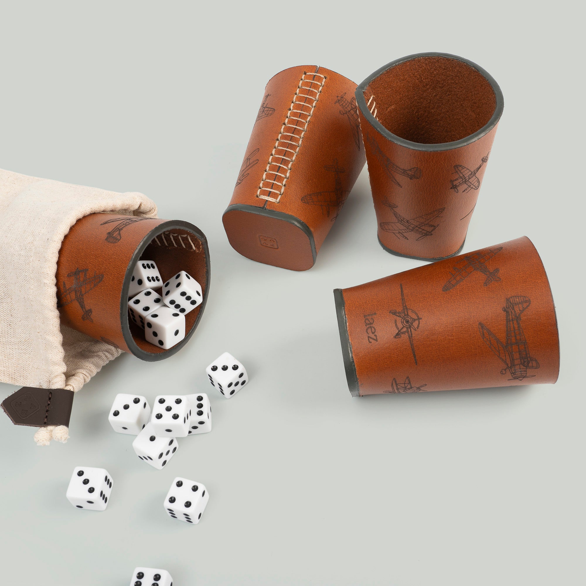 Three dice cups arranged neatly beside a bag filled with colorful dice, ready for a game night.