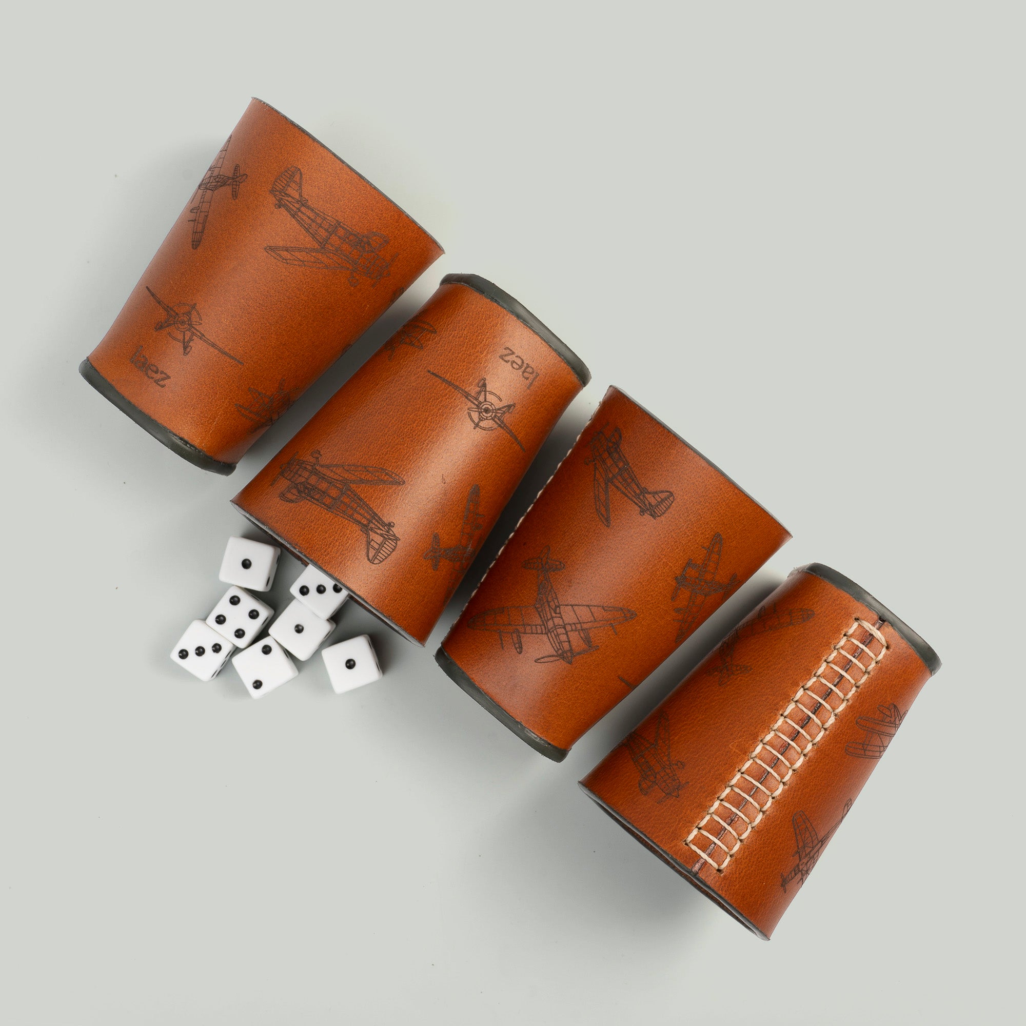 Four dice cups arranged neatly beside a cup filled with colorfu dice