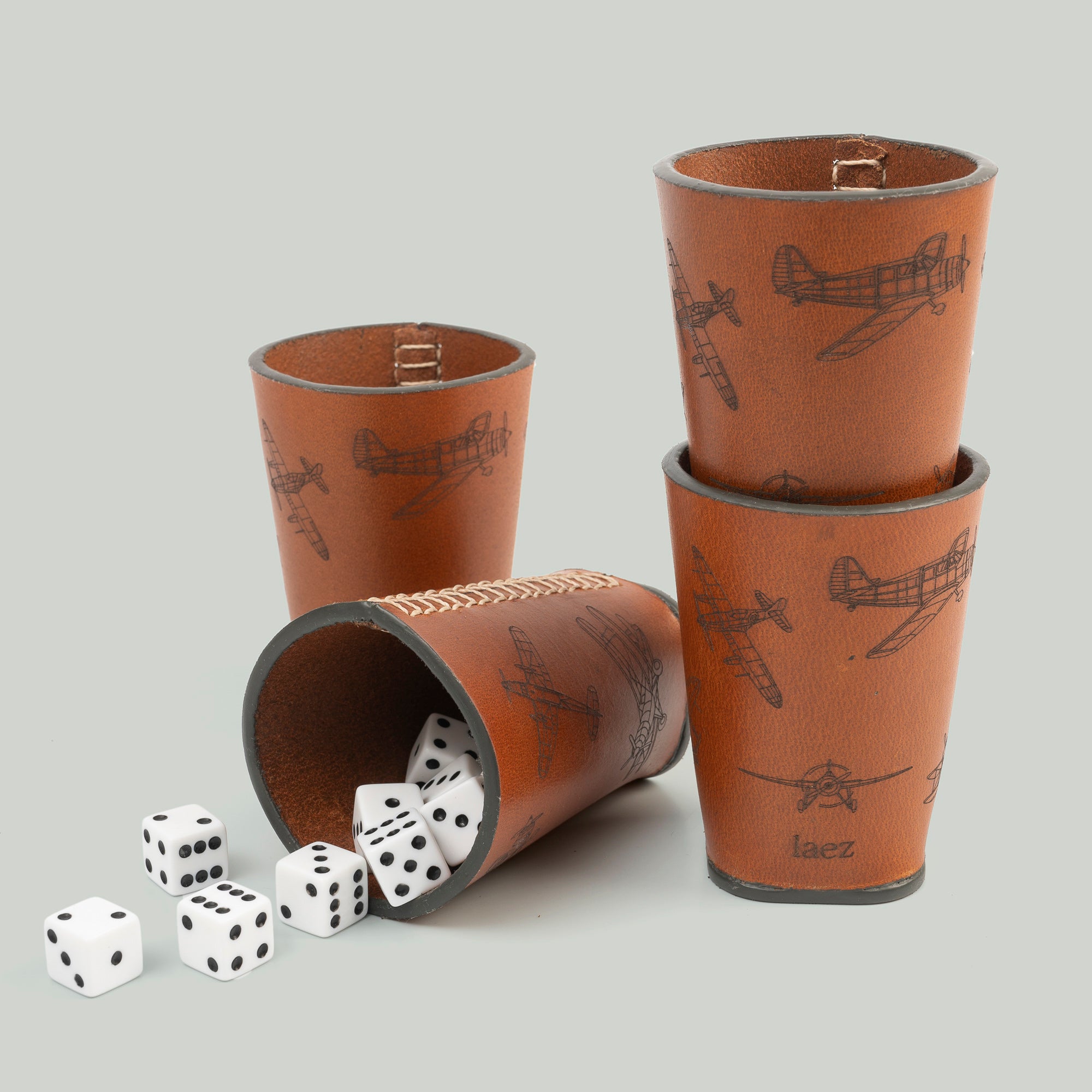 Four dice cups arranged neatly beside a cup filled with colorfu dice