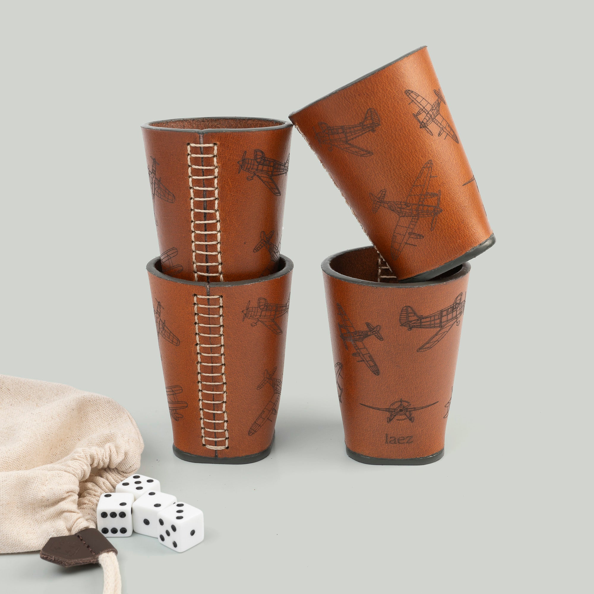  Four dice cups arranged neatly beside a bag filled with dice, ready for a game night.