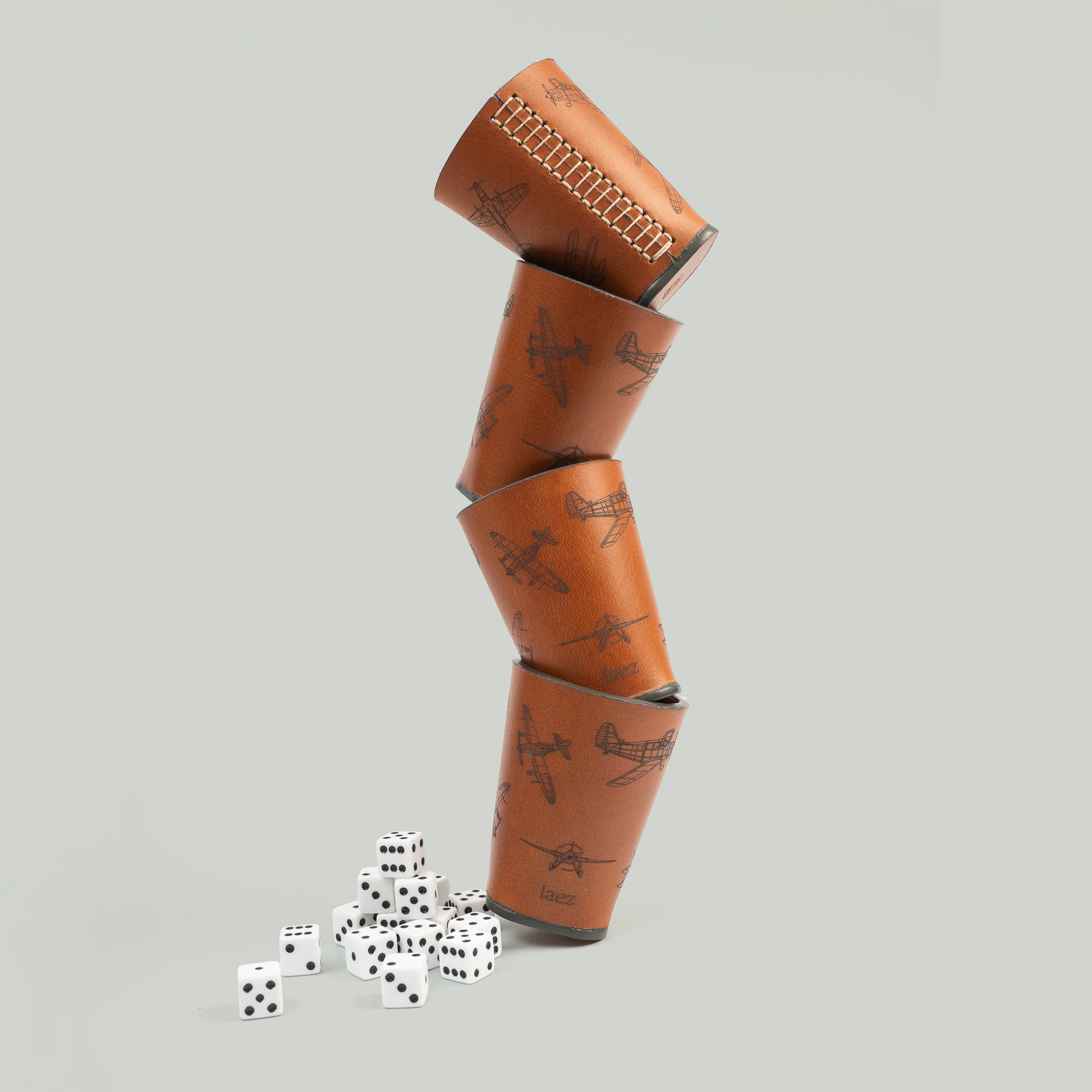Four dice cups stacked up beside many dices