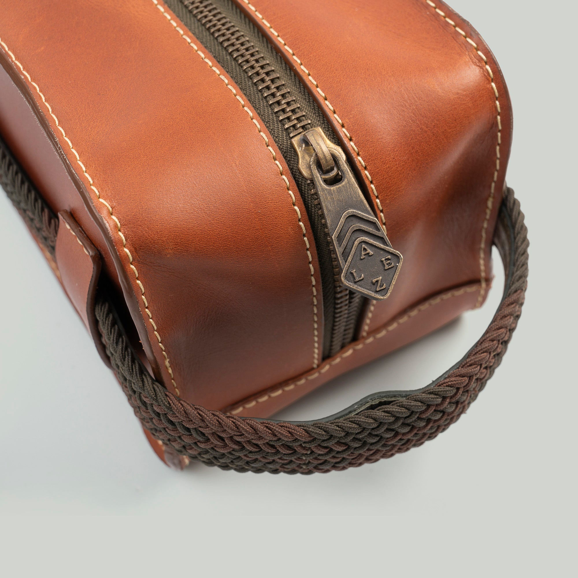 A brown leather travel pouch containing a toothbrush, toothpaste, and various toiletry items for personal care.