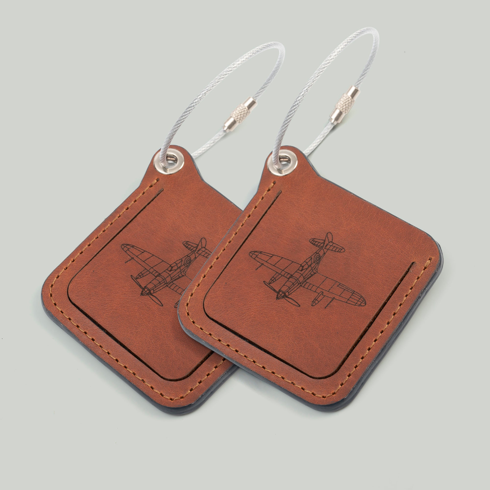 Two leather luggage tags with metal rings, elegantly designed for travel organization and personalization.