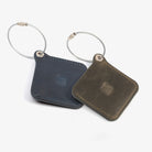 Two leather luggage tags with metal rings, elegantly designed for travel organization and personalization.