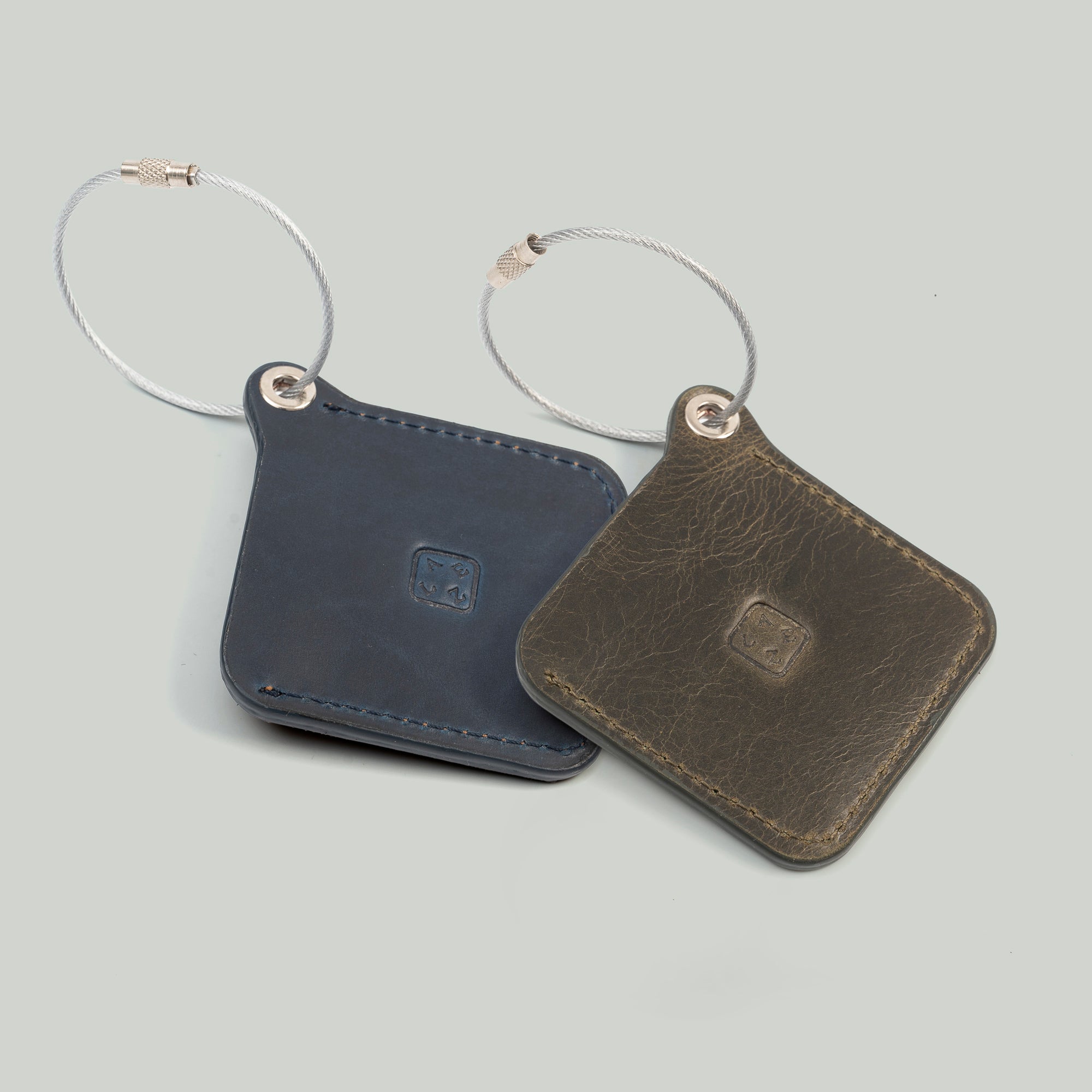 Two leather luggage tags with metal rings, elegantly designed for travel organization and personalization.