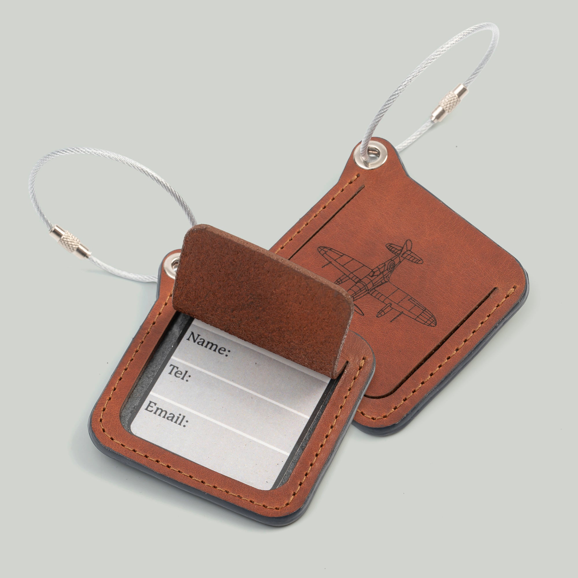 Two leather luggage tags with metal rings, elegantly designed for travel organization and personalization.